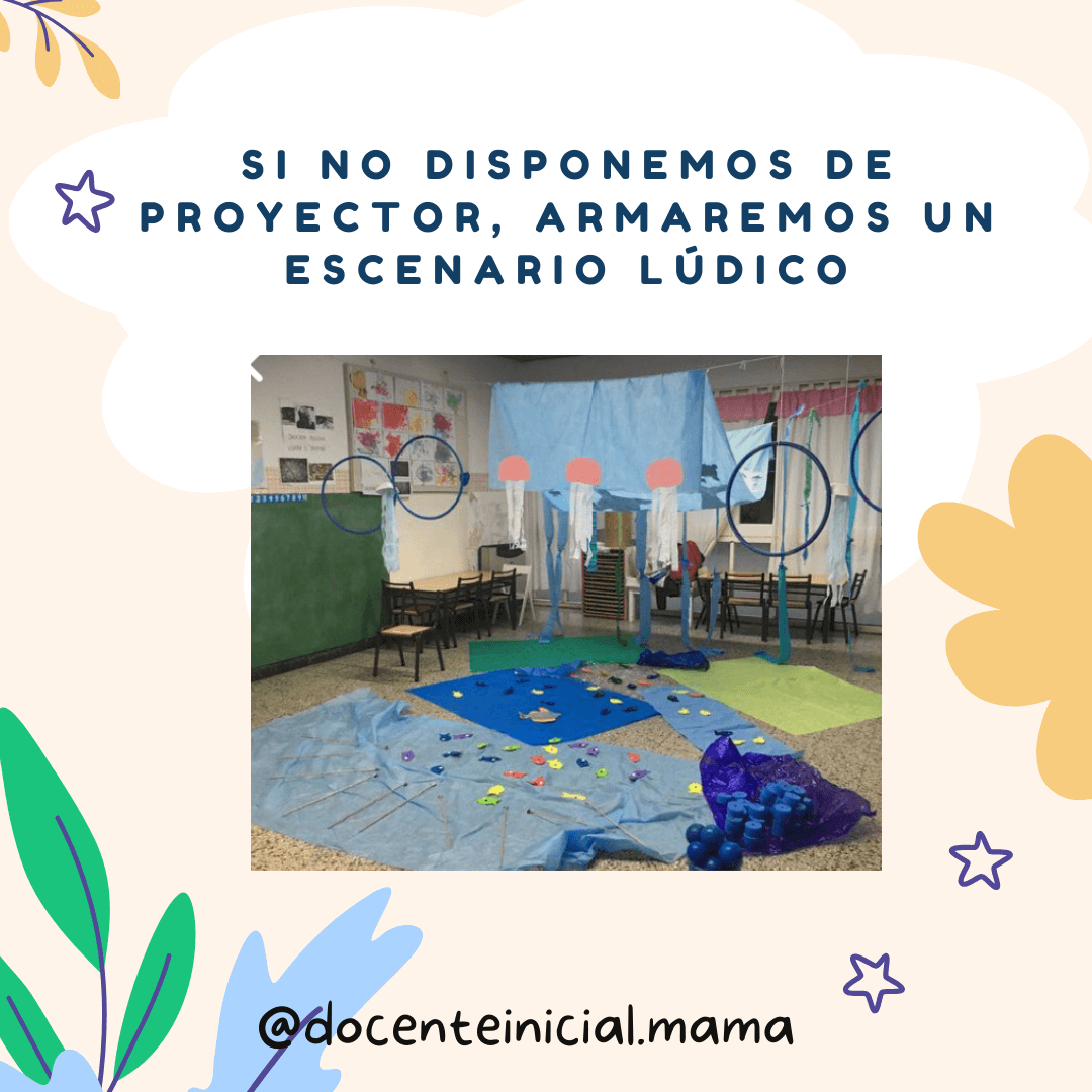 Escenario lúdico armado en el aula con temática marina Aula preparada con telas azules, aros colgantes, paneles y objetos distribuidos en el piso para un juego inspirado en el fondo del mar.