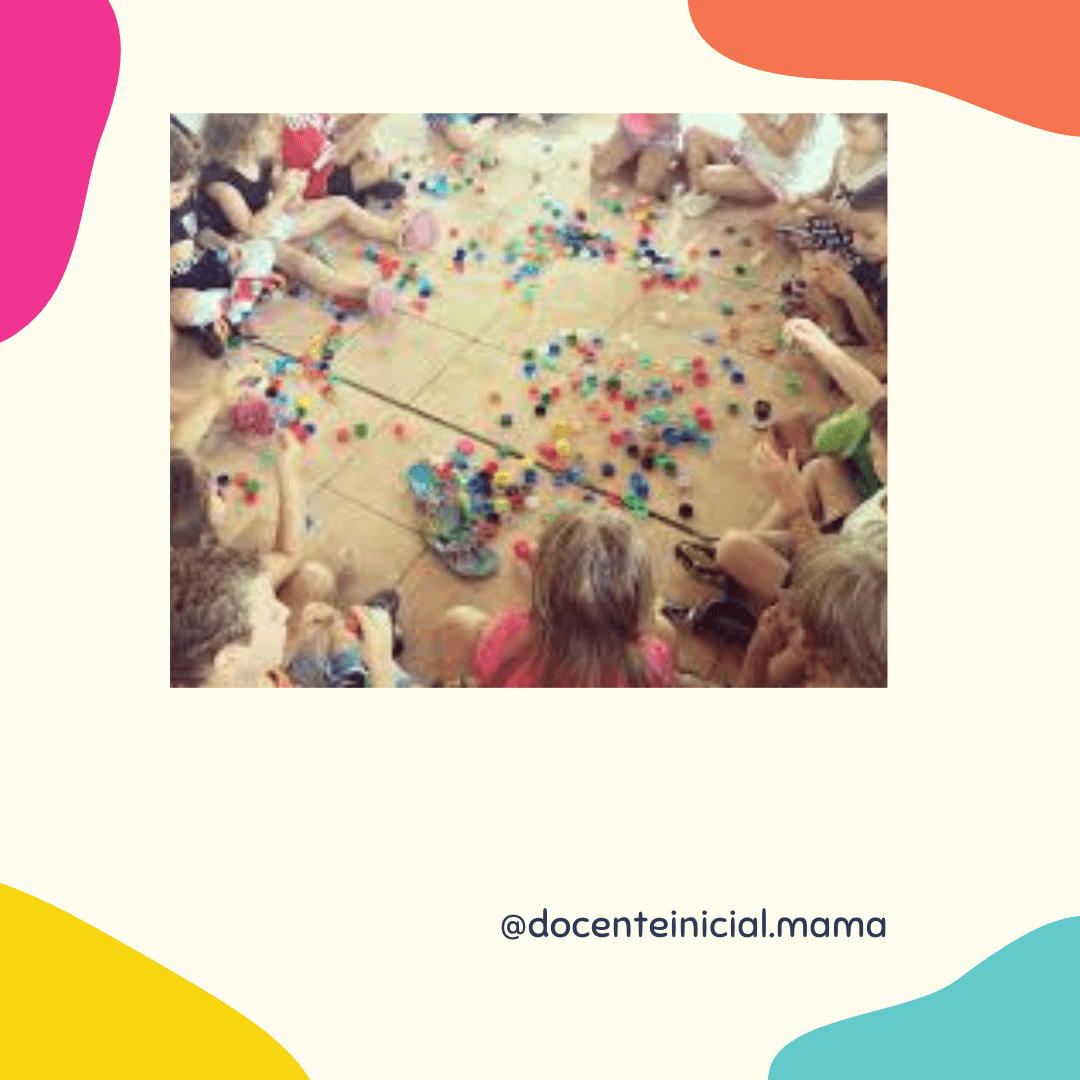 Grupo de niños sentados en círculo sobre el piso, rodeando muchas piezas pequeñas de colores esparcidas en el centro durante una actividad de juego o clasificación.