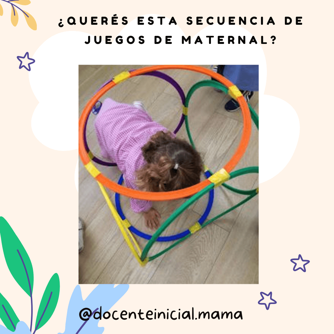 Una niña pequeña aparece agachada dentro de una estructura hecha con aros plásticos de varios colores, sobre piso de madera en un aula.