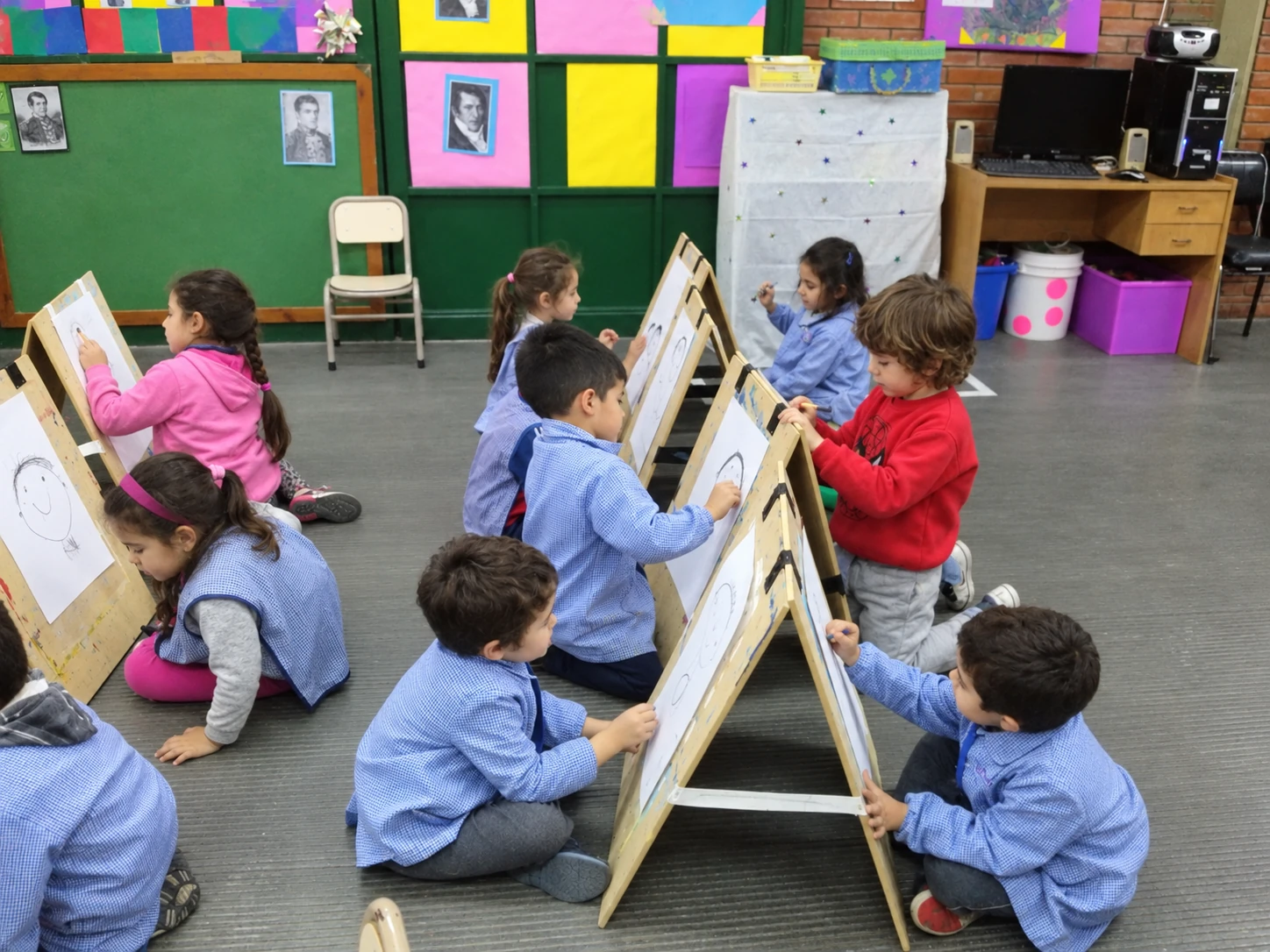 Niños y niñas dibujando en caballetes dentro de un aula Recreación fotográfica de niños y niñas dibujando en caballetes de madera dentro de una sala de jardín.