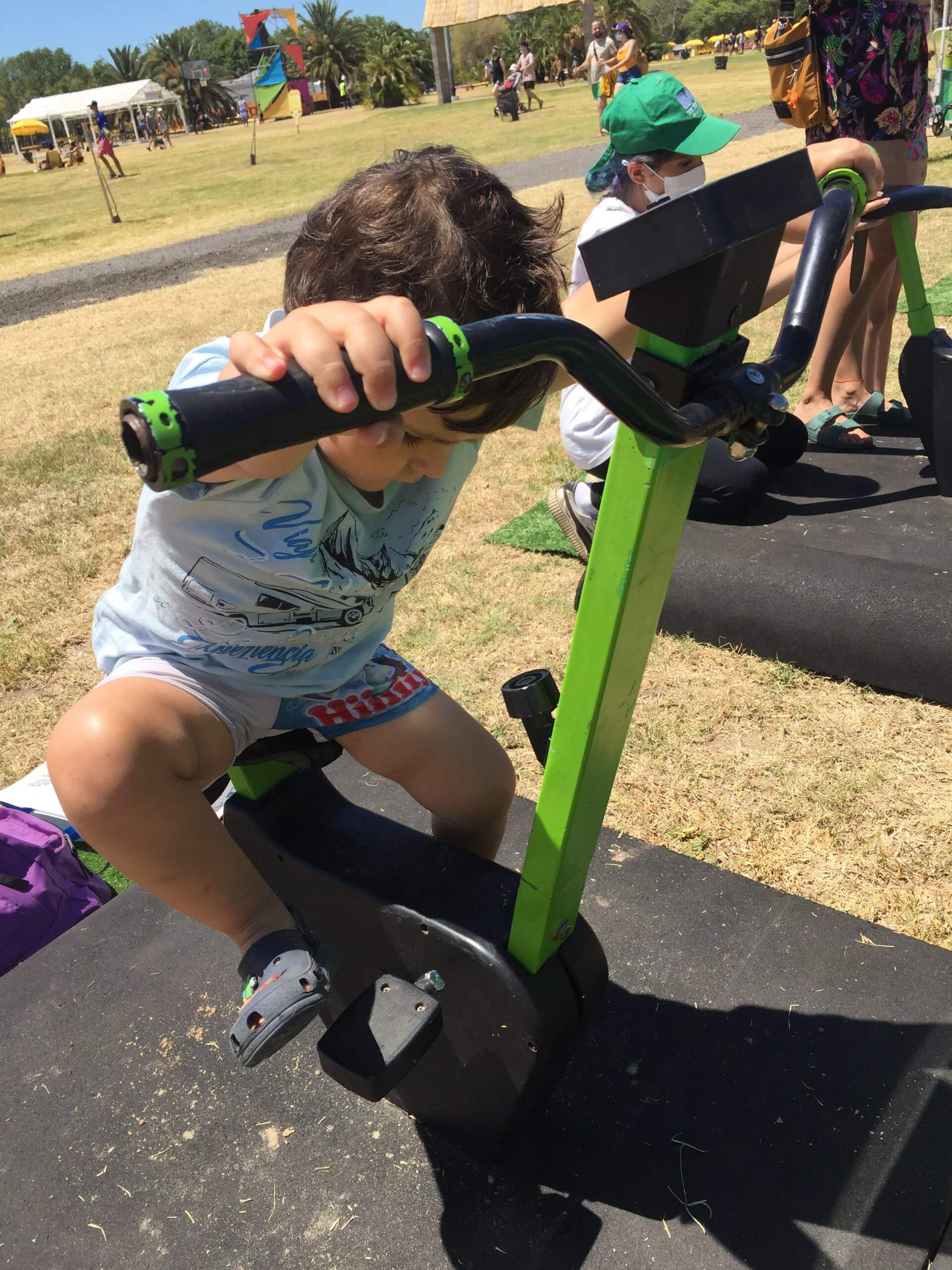 Juego y movimiento al aire libre Un niño se sostiene de los manubrios de un juego en un espacio recreativo al aire libre.